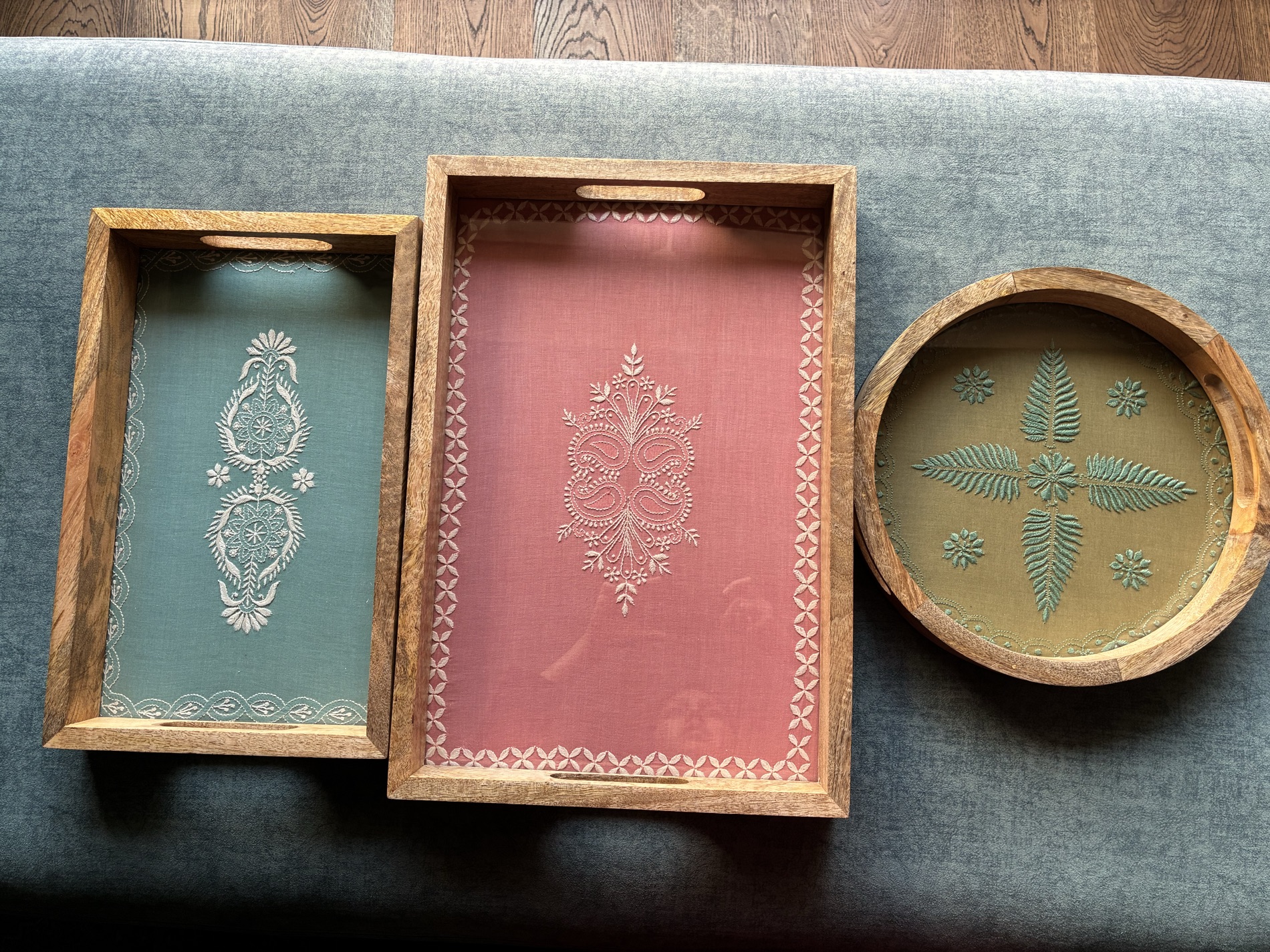 Three handcrafted chikankari trays in sage green, rose pink and olive, in mango wood frames